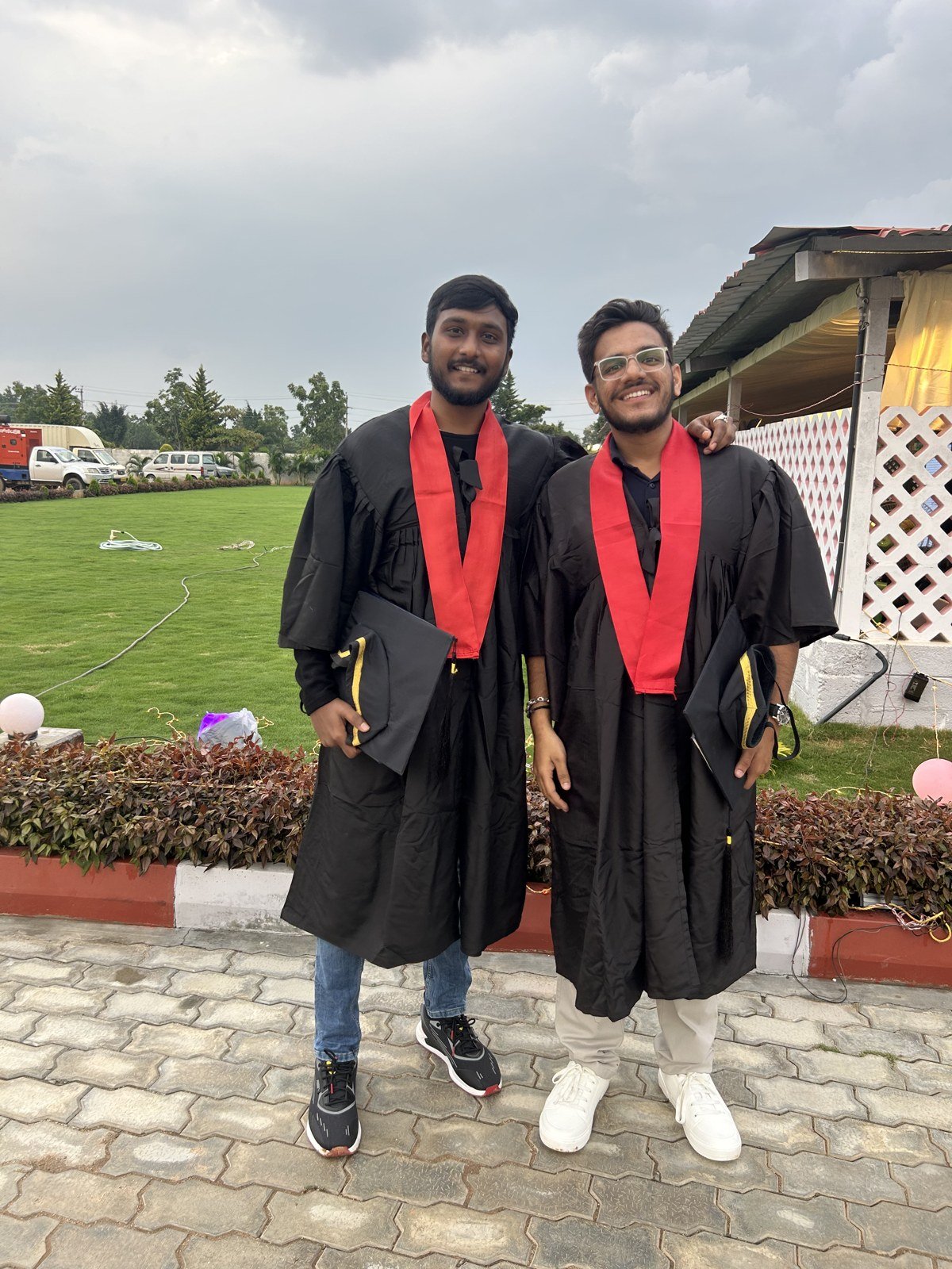 Akash and a fellow graduate in black gowns with red stoles